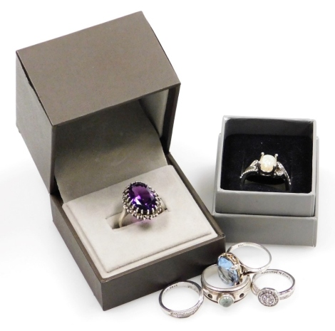 Six silver and other dress rings, comprising a purple paste stone and marquisette cluster ring, a crossover ring, aquamarine paste stone set ring, a stone set circular dress ring with Emily and Matthew inscription and an opal dress ring, four marked 925, 