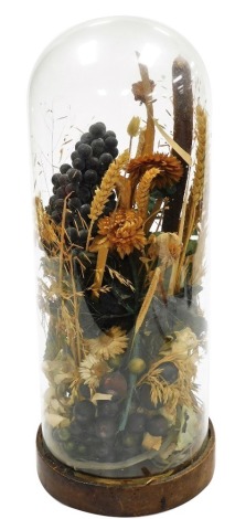 An early 20thC dried floral arrangement, with faux fruit, contained under a glass dome, on a wooden base, the dome and base 45cm high. (AF)