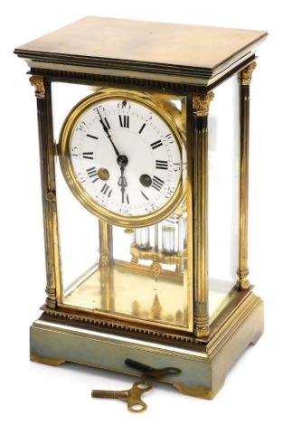 A late 19thC French brass cased mantel clock, the circular white enamel dial bearing Roman and Arabic numerals, eight day movement with coil strike and mercury pendulum, with key and pendulum, the case with outswept pendulum and four Corinthian fluted qua