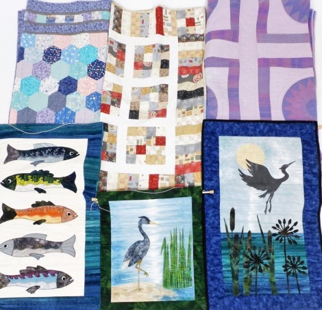 A group of patchwork quilts and wall hangings, to include double quilt in shades of purple, blue and pink, 200cm x 200cm, a patchwork heron wall hanging, 56cm x 50cm, etc.