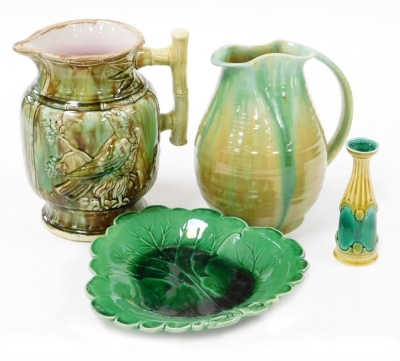 A majolica jug, with applied bird and branch decoration, 22cm high, a 19thC leaf shaped plate, 24cm wide, a blue and yellow glazed jug with a shaped rim, 22cm high, and a majolica bud vase, with stamp to underside, 14cm high. (4)