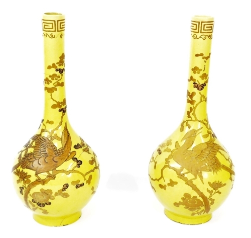 A pair of 19thC Chinese yellow ground bottle vases, decorated in gilt and enamels, each with a phoenix perched amongst prunus blossom, beneath a 'Greek key' and foliate scroll top rim border, 85cm high. (AF)