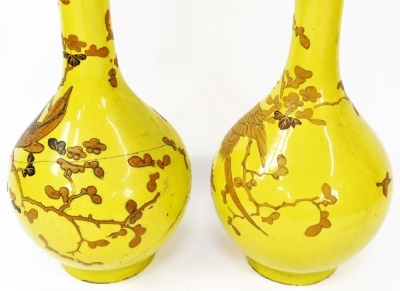 A pair of 19thC Chinese yellow ground bottle vases, decorated in gilt and enamels, each with a phoenix perched amongst prunus blossom, beneath a 'Greek key' and foliate scroll top rim border, 85cm high. (AF) - 3