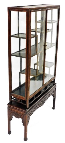 A Chinese hardwood glazed display cabinet, with various shelves raised on a platform stand with blind fret details, on square moulded legs, 93cm wide, 165cm high.