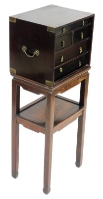 A Chinese brass bound hardwood chest, with five various drawers and brass drop handles, on an unassociated two tier stand, 41cm wide.