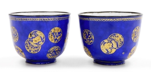 A pair of 19thC Chinese Canton enamel wine cups, decorated with overlapping gilt roundels on a blue ground, 6cm high.