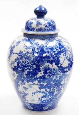 A Japanese Meiji period Seto blue and white porcelain vase and cover, of ovoid form, profusely decorated trees, flowers and blossom, within geometric and scroll banding, 56cm high. (AF)