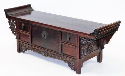 A Chinese stained wood writing table, carved with scrolling prunus blossom fret work, having a pair of central doors, flanked by two small drawers, 34cm high, 92cm wide, 17.5cm deep.