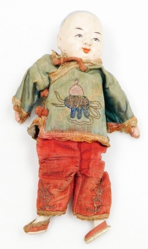 A late 19thC Chinese papier mache and wooden doll, with embroidered red trousers and green tunic, 19.5cm high.