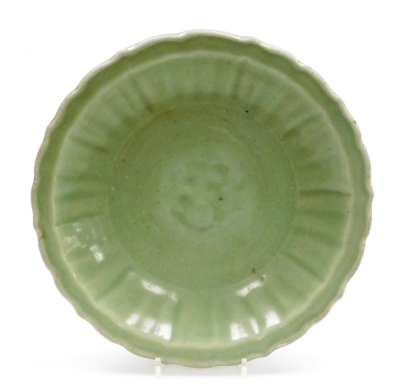 A Chinese celadon dish, with incised decoration within a wave border, probably 18thC, 32cm wide.
