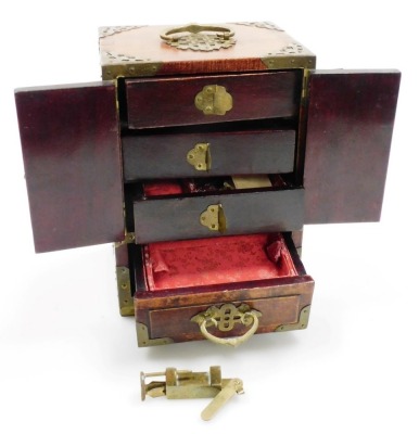 A Chinese hardwood jewellery casket, with brass handle and pierced mounts, carved simulated jade panels, the two hinged doors enclosing three drawers, above a further drawer to base, 22cm high, 15cm wide, 12cm deep, with lock and key. - 8