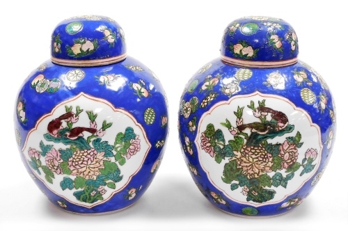 A pair of 20thC ginger jars and covers, decorated with birds on flowering branches against a blue ground, six character Qianlong mark in red to underside 27cm high.