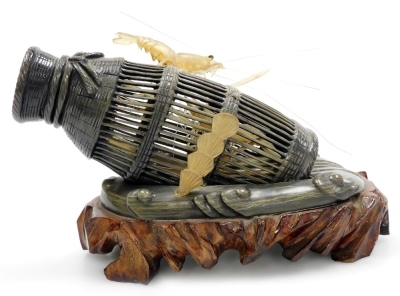 An Oriental horn carving of shrimps in a shrimp pot, on a hardwood base, 15cm wide.