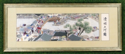 A mid 20thC embroidery landscape picture, with oarsmen and boats on a river, an arched bridge above with many figures and market stalls, inscribed on a panel to the right signed, 29cm x 88cm. - 2