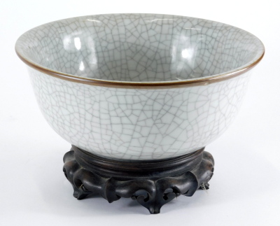 A 20thC Chinese crackle glaze everted bowl, on a hardwood lotus carved stand, 24cm diameter.