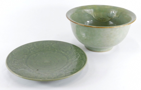 A celadon saucer dish, embellished with peony bud and swirling leaves, 29cm diameter, and a celadon glazed Chinese everted bowl (AF), 28cm diameter. (2)