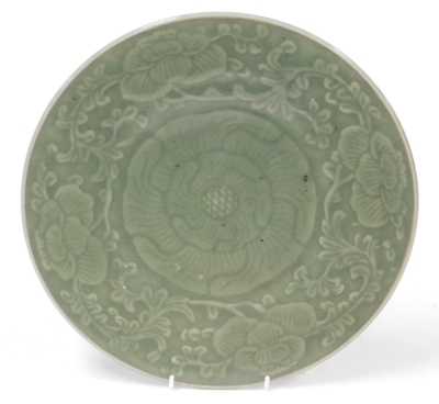 A celadon saucer dish, embellished with peony bud and swirling leaves, 29cm diameter, and a celadon glazed Chinese everted bowl (AF), 28cm diameter. (2) - 4