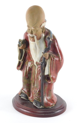 A Chinese sang de boeuf glazed figure, of Shou Lau holding a peach and his gnarled staff, 28cm high, with base. (AF)