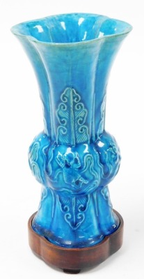 A 19thC Chinese turquoise ground porcelain Gu vase, decorated in relief with precious objects and lappets, 21cm high, with hardwood stand. - 2