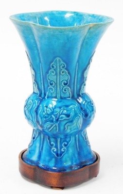 A 19thC Chinese turquoise ground porcelain Gu vase, decorated in relief with precious objects and lappets, 21cm high, with hardwood stand. - 3