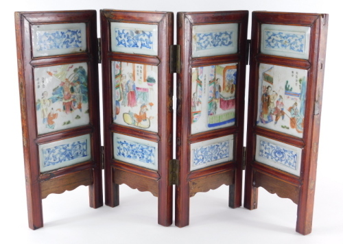 A 19thC Chinese porcelain table screen, four fold, with blue and white panels over and beneath central famille rose enamelled court scenes with inscriptions to the centre, 41cm high.