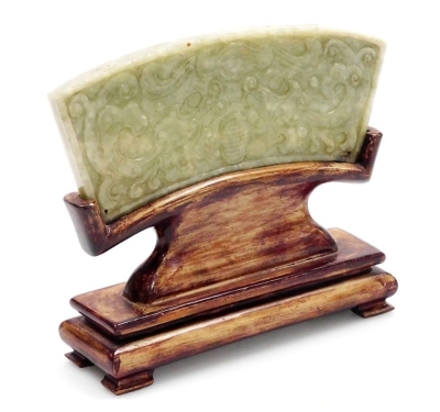 A Chinese carved jade plaque, carved ub klow relief with archaic designs, on a hardwood stand, 11.5cm high overall.