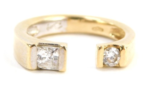 A diamond dress ring, two torc design set with square cut and round brilliant cut diamonds, the round brilliant cut diamond approx 0.25cts, the square cut diamond approx 0.18cts, in tension setting, on a yellow metal band, marked 585, ring size R, 6g all