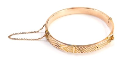 A 9ct rose gold hinged bangle, the half hinged design with hatched detail and buckle, 6cm wide, with safety chain, 16.7g all in, boxed.