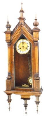 A walnut Vienna wall clock, the arched top with turned finials, with white enamel numeric dial, carved cresting, 90cm high, 34cm wide, 17cm deep.