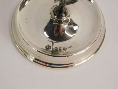 A George V silver ring stand, with well and antelope centre, London 1922, weighted base, 2½oz gross. - 2