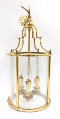 A brass lantern, with an arched top and three fittings and four glass sections, 56cm high before hanging.