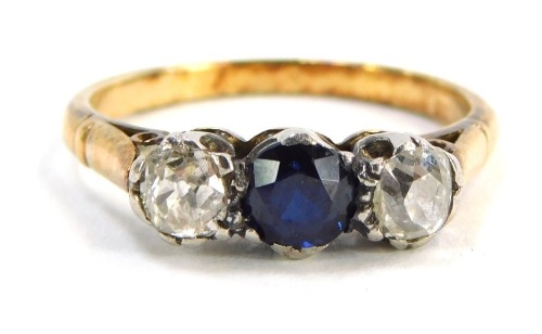 A sapphire and diamond three stone ring, the round brilliant cut sapphire in claw setting, measuring 4.8mm x 3.6mm, flanked by two old cut diamonds, each approx 0.25cts, with etched design shoulders in a raised platinum setting, yellow metal stamped 18, s