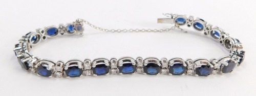 A tennis bracelet, with blue and white paste stones and safety chain, white metal unmarked, clasp stamped 1.43, 20cm long overall, 22.2g all in.