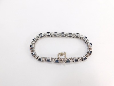 A tennis bracelet, with blue and white paste stones and safety chain, white metal unmarked, clasp stamped 1.43, 20cm long overall, 22.2g all in. - 2