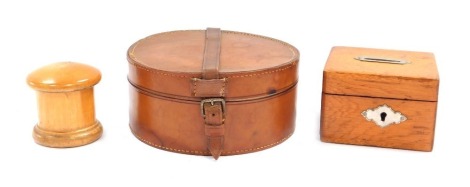 Two vintage treen boxes, comprising a turned needle case, 6cm high with mushroom top, a oak money box, with plated lock and key slot, 7cm high, and a leather collar box, 16cm diameter. (3)