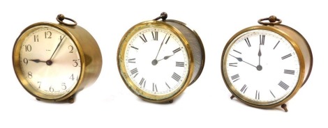 Three brass cased carriage timepieces, each of drum form, with eight day movement, two with white enamel and Roman numeric dials, another with silvered numeric dial, each 10cm diameter. (3)