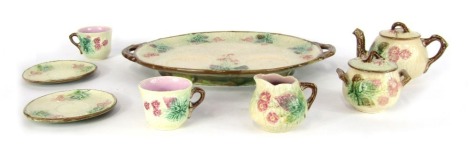 A French majolica tete a tete, comprising serving tray, milk jug, sugar bowl, two cups and saucers, and a teapot, cream ground with brown borders and floral detailing.