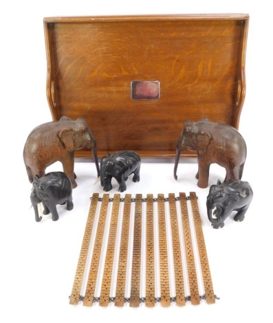 Carved wooden trinkets, comprising a set of three ebony and bone elephants, 10cm high, two carved wooden elephants, 18cm high, an oak and silver plated galleried tray, 52cm x 40cm, and a wooden rung pot stand. (a quantity)