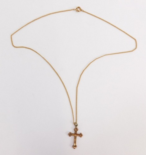 A crucifix pendant and chain, the crucifix with floral scroll decoration and single loop top, on a fine link chain, stamped 9ct, the crucifix 2.5cm high, the chain 40cm long, 2.6g all in.