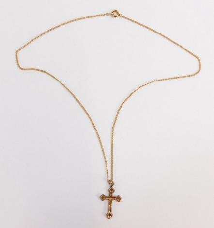 A crucifix pendant and chain, the crucifix with floral scroll decoration and single loop top, on a fine link chain, stamped 9ct, the crucifix 2.5cm high, the chain 40cm long, 2.6g all in.