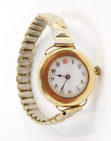 A 1960's lady's wristwatch, with small circular watch head, with white enamel numeric dial, with gold point markers, in a yellow metal case unmarked believed to be 9ct, 2cm diameter, on a plated expanding strap, 24.3g all in.