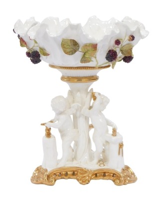 A Victorian Moore Brothers porcelain comport, the flared bowl with applied blackberry detail, on a tripod base, with three cherubs, with gilt detailing, unmarked, 30cm high.