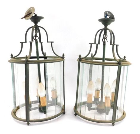 A pair of brass hanging lanterns, each cylinder form, with four fittings and various glass panels, each lantern 48cm high before hanging.