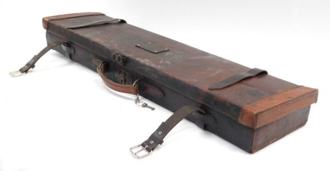 A leather gun carrying case, with two outer buckle supports, opening to reveal a red lined interior with key, 83cm wide, 21cm deep, 7cm high.