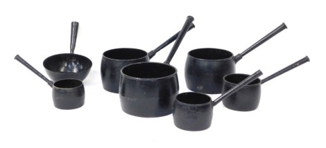 Seven black painted metal pans.