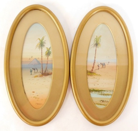 Crofts (20thC School). Eastern desert scenes, gouache, 22cm x 8cm, in oval gilt frames. (2)