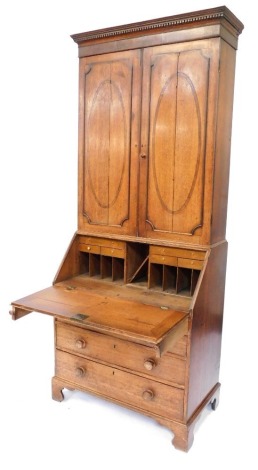 A late 19thC oak bureau bookcase, with a dentil cornice above two panelled doors, the base with a fall and four long drawers, terminating in bracket feet, 220cm high, 92cm wide, 50cm deep.