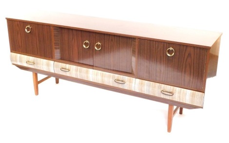 A 1960's sideboard, melamine two tone finish, brass curved handles, tapered legs, 72cm high, 180cm wide, 41cm deep.