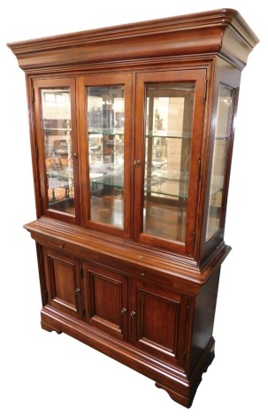 A continental cherrywood display cabinet, with moulded cornice above three glazed doors, with two long shelves, each divided into three square sections, above two drawers, three cupboard base, terminating in bracket feet, 200cm high, 133cm wide, 48cm deep