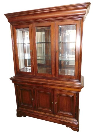 A continental cherrywood display cabinet, with moulded cornice above three glazed doors, with two long shelves, each divided into three square sections, above two drawers, three cupboard base, terminating in bracket feet, 200cm high, 133cm wide, 48cm deep